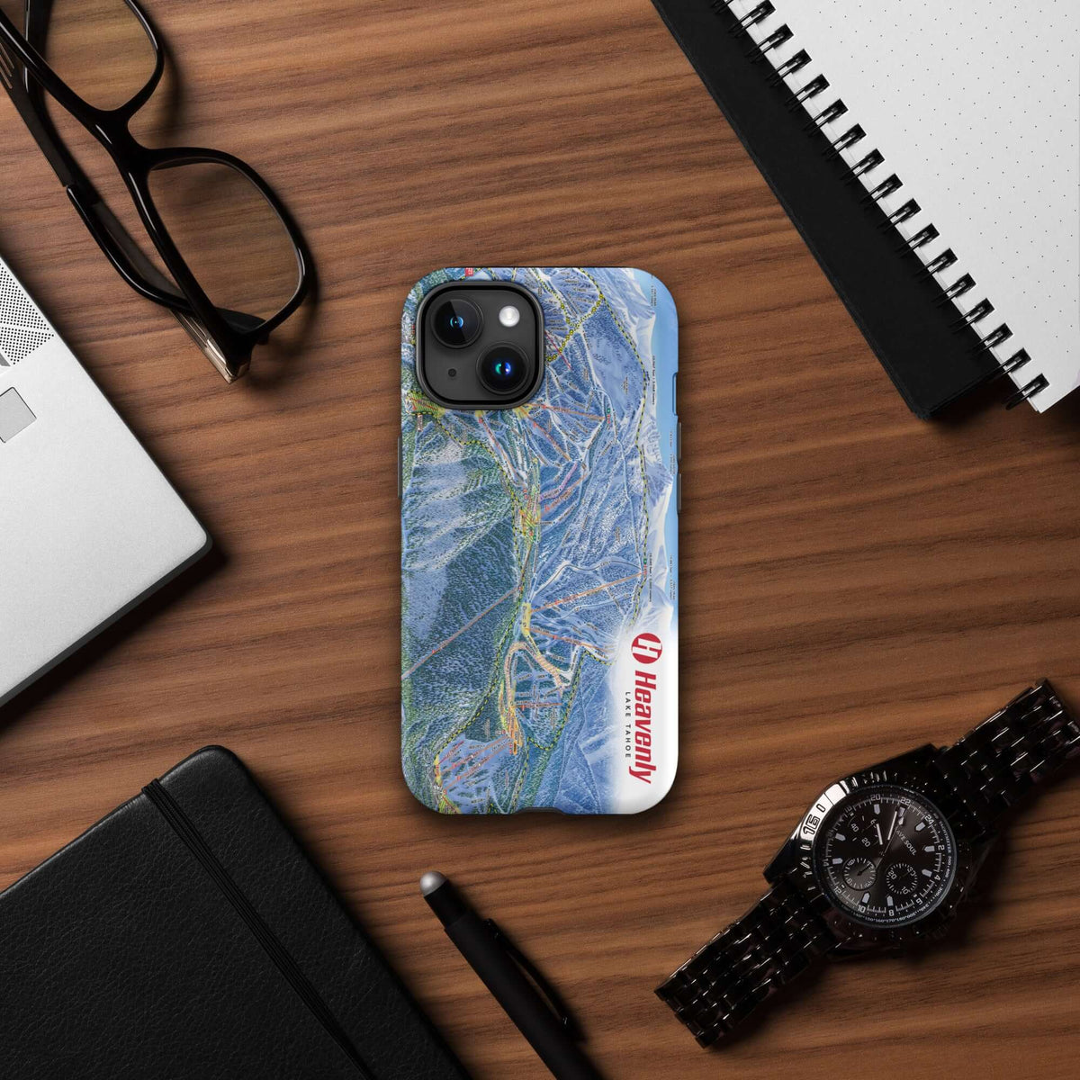 Heavenly Trail Map Rugged iPhone Case featuring Mtns Co Trail Map Logo on wooden desk with accessories.