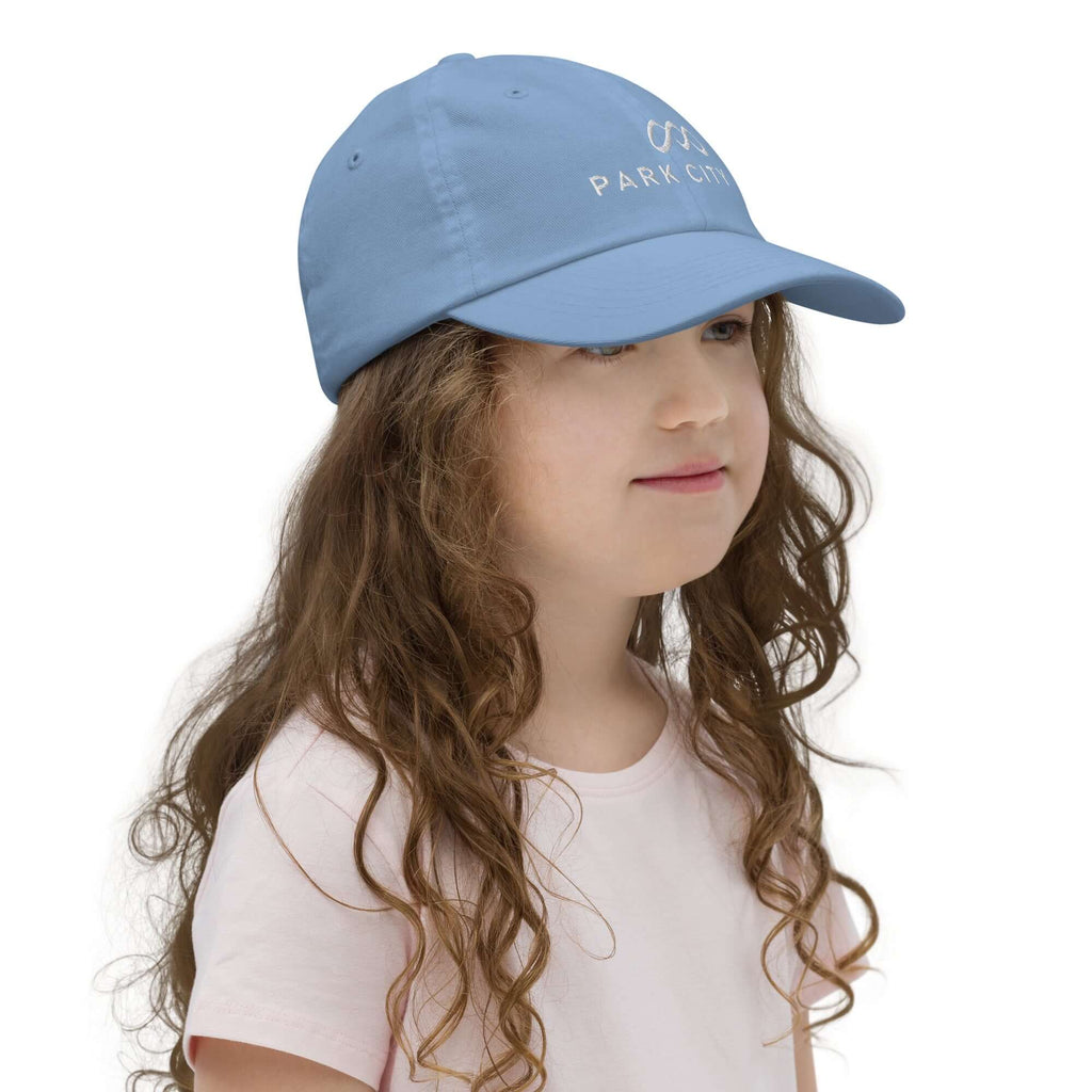 Park City Youth Baseball Cap worn by a girl showcasing Mtns Co Trail Map Logo.