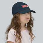 Crested Butte Youth Baseball Cap worn by a girl, showcasing Mtns Co official licensed ski resort apparel.