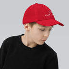 Park City Youth Baseball Cap worn by a child showcasing Mtns Co Trail Map Logo, perfect for sunny days outdoors.