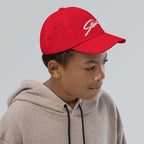 Stowe Youth Baseball Cap on a boy's head, showcasing the official Mtns Co Trail Map Logo in a vibrant red.