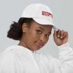 Crested Butte Youth Baseball Cap worn by a girl in a white hoodie, promoting official ski resort apparel by Mtns Co.