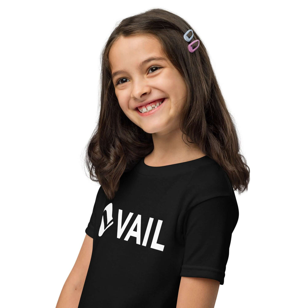 Vail Youth T-Shirt worn by a girl with a big smile, showcasing Mtns Co Trail Map Logo, perfect for outdoor play.