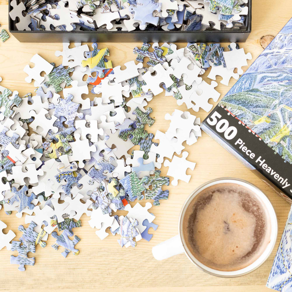 Heavenly Ski Resort Jigsaw Puzzle – 500 Pieces pieces scattered with a coffee cup on a wooden table, by Mtns Co.