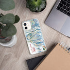 Park City Trail Map iPhone Case with Mtns Co logo on a wooden desk with plants and a laptop.